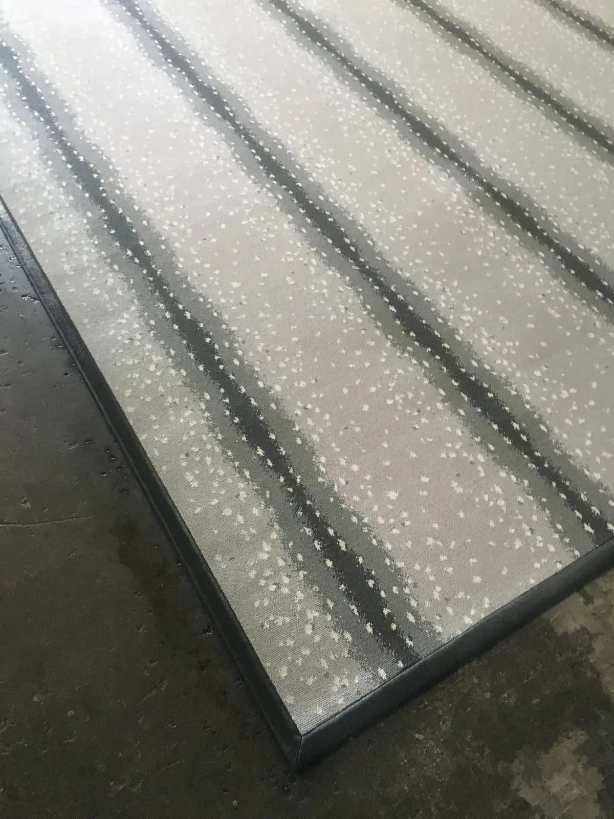 Pale striped rug with a narrow dark leather border finished with blindstitching